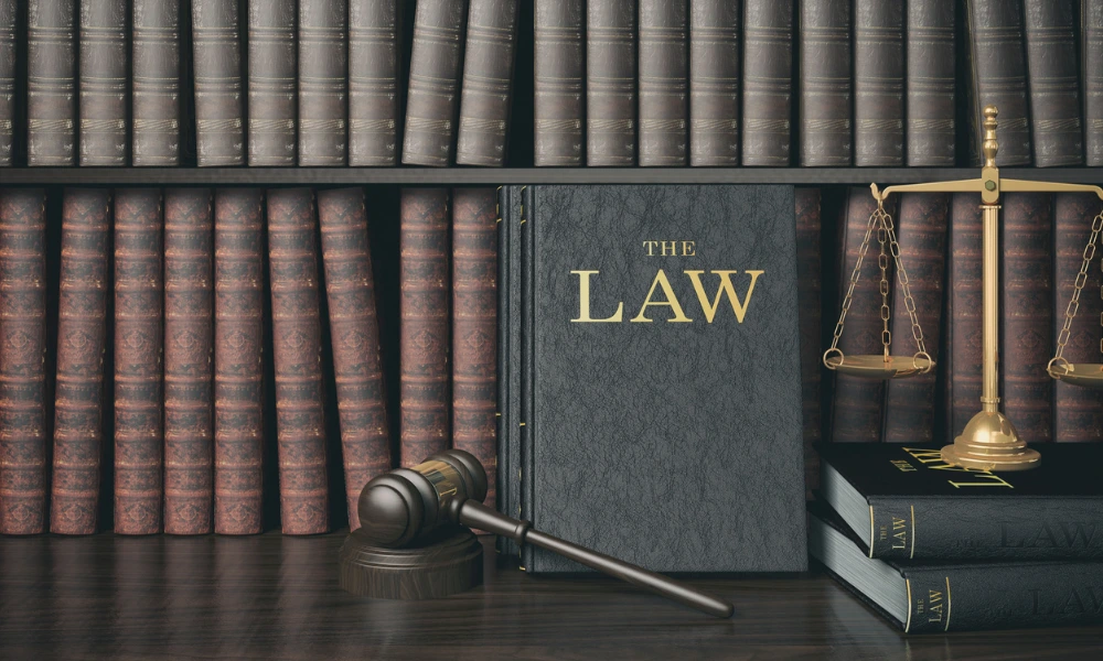 A law book, a gavel, and several books are arranged on a table, symbolizing legal study and practice.